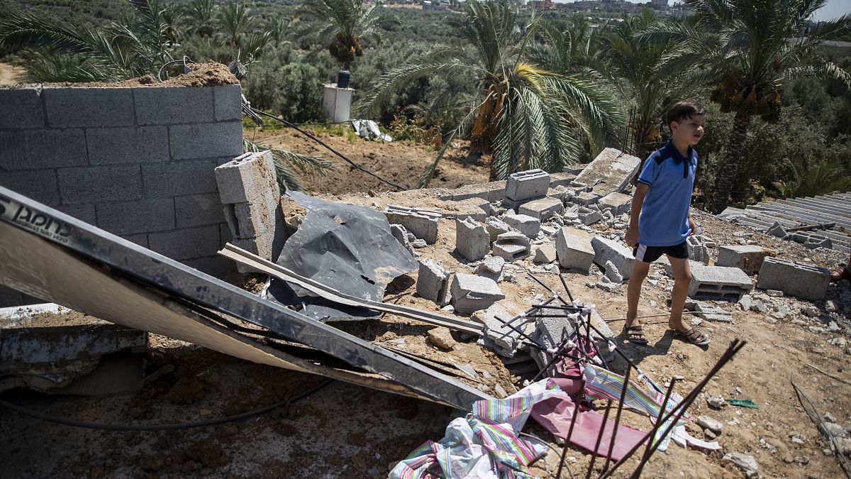 طفل فلسطيني يقف على أنقاض بيته المهدم بسبب القصف الإسرائيلي