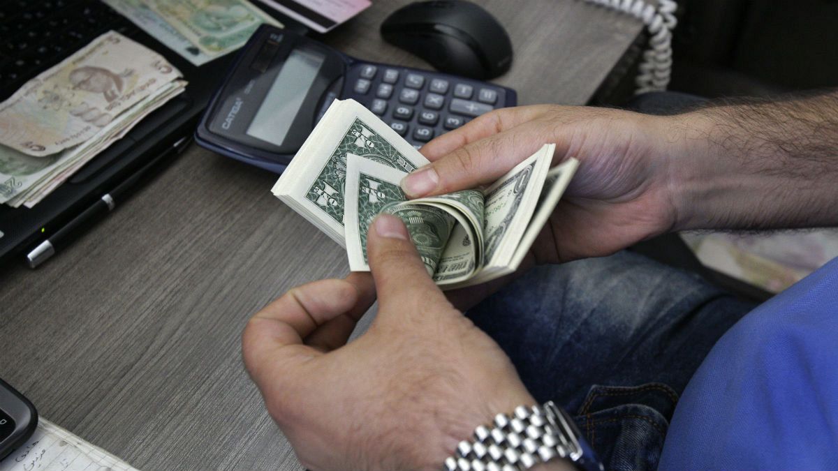 A currency exchange bureau worker counts U.S. dollars in downtown Tehran, Iran
