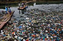 Oct. 2, 2016 file photo: a man guides a raft through a polluted canal littered with plastic bags and other garbage in Mumbai, India.