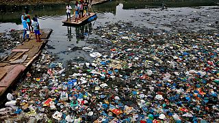 Oct. 2, 2016 file photo: a man guides a raft through a polluted canal littered with plastic bags and other garbage in Mumbai, India. 