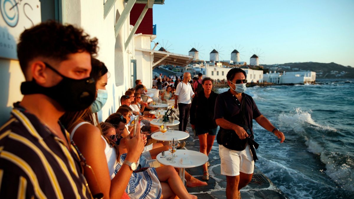 People, some of them wearing face masks against the spread of the new coronavirus, gather on Mykonos, Greece, Sunday, Aug. 16, 2020.