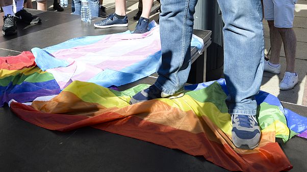 A man stands on a Rainbow Flag as he attends a demonstration of far-right activists against LGBT rights in Warsaw, Poland, Sunday, Aug. 16, 2020. A man stands on a Rainbow Flag as he attends a demonstration of far-right activists against LGBT rights in Warsaw, Poland, Sunday, Aug. 16, 2020.