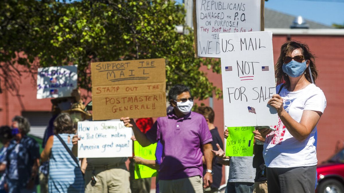 gather in front of the United States Post Office to protest recent changes to the USPS under new Postmaster General Louis DeJoy, Tuesday, Aug. 11, 2020 in Midland, Michigan