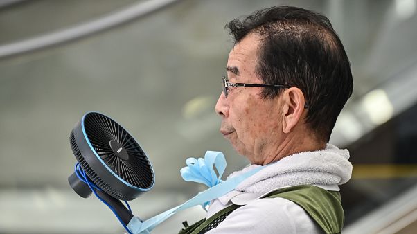 Tokyo'da serinlemeye çalışan yaşlı bir adam Tokyo'da serinlemeye çalışan yaşlı bir adam