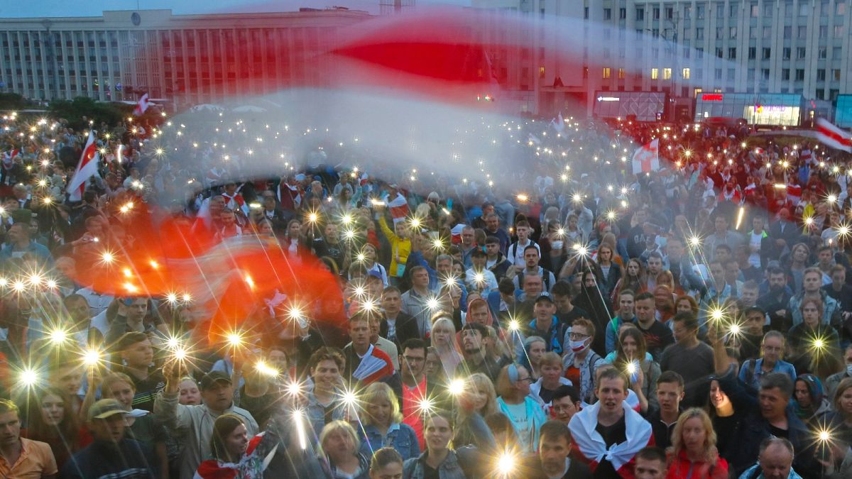 Belarusian opposition supporters light phones lights and wave an old Belarusian national flags during a protest rally in front of the government building Wednesday, Aug. 19, .