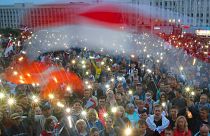 Belarusian opposition supporters light phones lights and wave an old Belarusian national flags during a protest rally in front of the government building Wednesday, Aug. 19, .