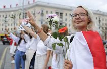 Belarusians protesting against disputed presidential elections results hold flowers and flash victory signs during a protest in Victory Square in Minsk, Belarus. August 20