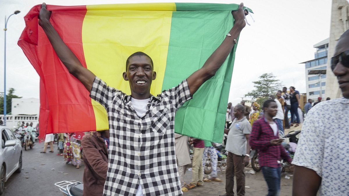 A man holds a national flag as he celebrates with others in the streets in the capital Bamako after a mutiny in Mali.