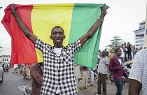 A man holds a national flag as he celebrates with others in the streets in the capital Bamako after a mutiny in Mali.