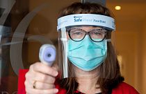 Avustralya'nın Melbörn kentinde bir sağlık çalışanı insanların koronavirüs olup olmadıklarını anlamak için vücud ısılarını ölçüyor