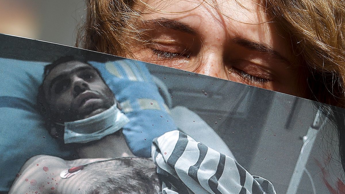 Egy nő egy bántalmazott férfi fotóját tartja az egyik minszki kórház előtt