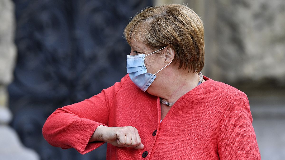 German chancellor Angela Merkel shows her elbow for a greeting in Duesseldorf, Germany, Tuesday, Aug. 18, 2020. 