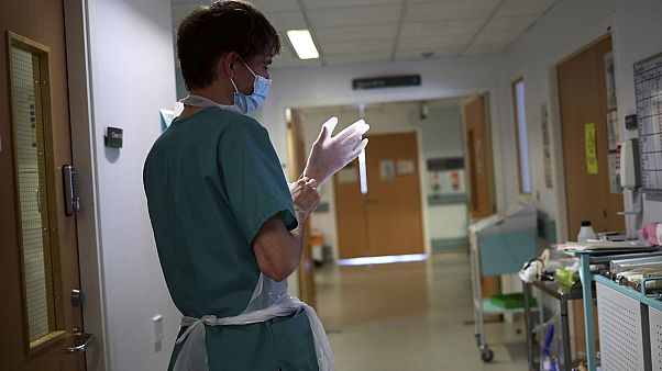 A junior doctor dons PPE to visit a patient. A junior doctor dons PPE to visit a patient.