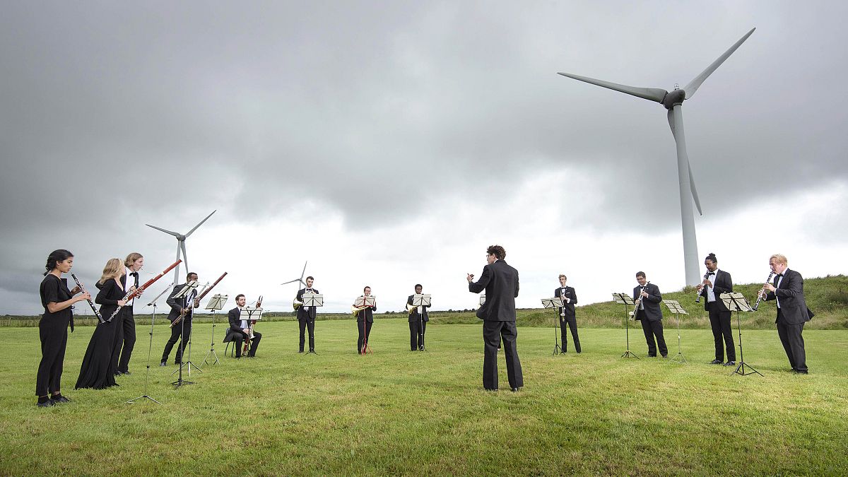 Orchestra for the Earth performs under wind turbines in Delabole, UK. 