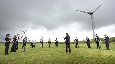 Orchestra for the Earth performs under wind turbines in Delabole, UK. Orchestra for the Earth performs under wind turbines in Delabole, UK.