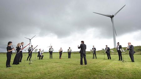 Orchestra for the Earth performs under wind turbines in Delabole, UK.