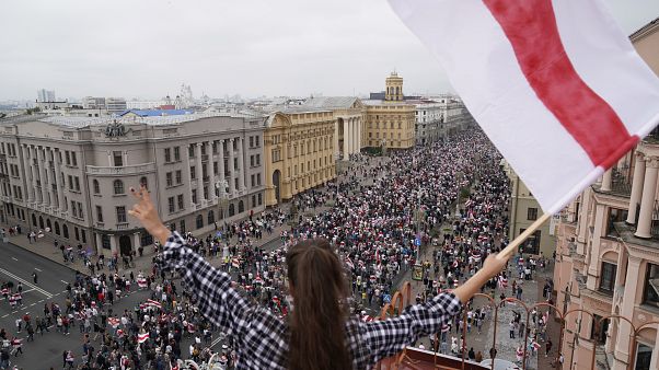 Eine Frau protestiert mit der alten belarussischen Nationalflagge auf einem Dach am Unabhängigkeitsplatz in Minsk Eine Frau protestiert mit der alten belarussischen Nationalflagge auf einem Dach am Unabhängigkeitsplatz in Minsk