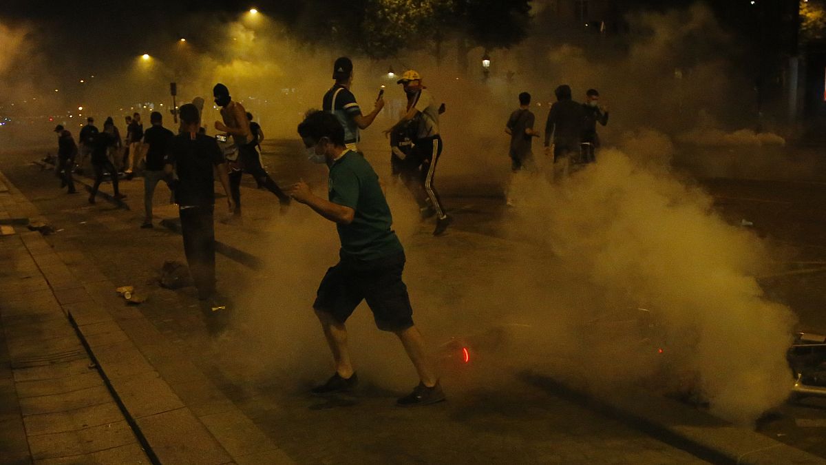 PSG supporters run through tear gas deployed by police forces on the Champs-Élysées after the Champions League final