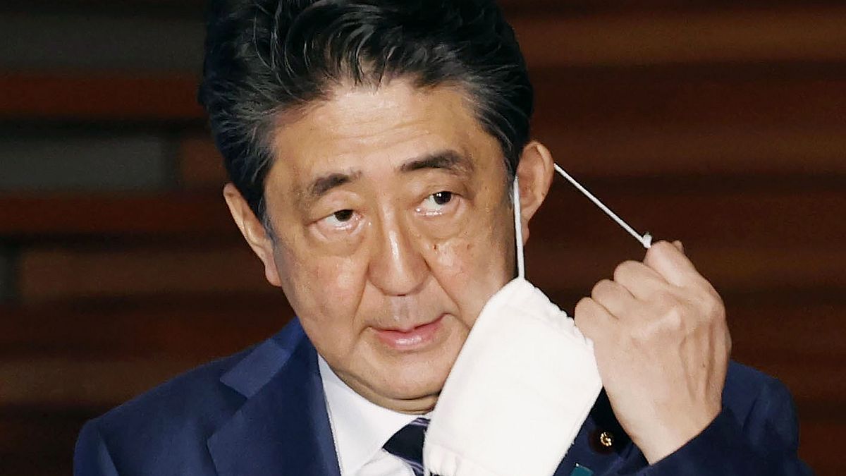 In this May 21, 2020, file photo, Japan's Prime Minister Shinzo Abe removes a face mask as he speaks at a press conference in Tokyo. 