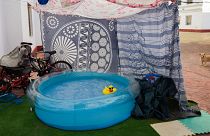 A rubber duck floats in a portable plastic pool that sits in the community housing association patio in Seville, Spain