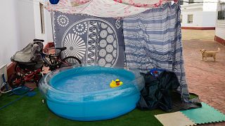 A rubber duck floats in a portable plastic pool that sits in the community housing association patio in Seville, Spain