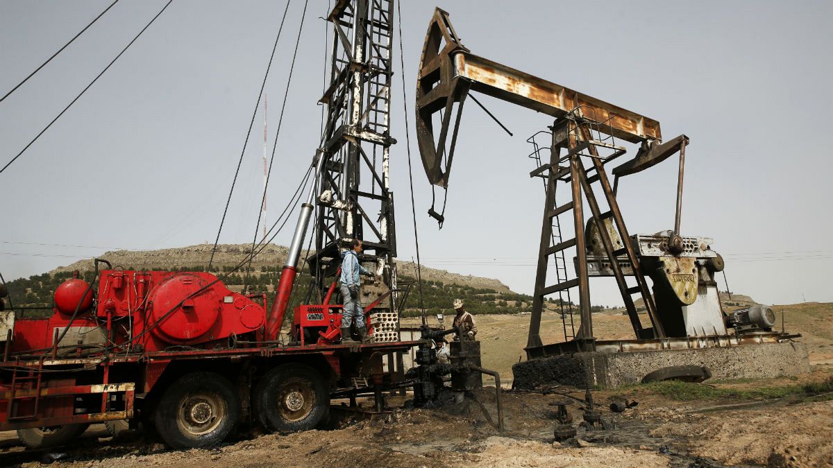 Syrian workers fixing pipes of an oil well at an oil field controlled by a U.S-backed Kurdish group