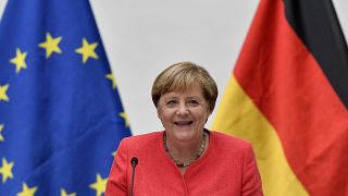 FILE: German chancellor Angela Merkel sits between a European and a German flag in Duesseldorf, Germany, Tuesday, Aug. 18, 2020. 