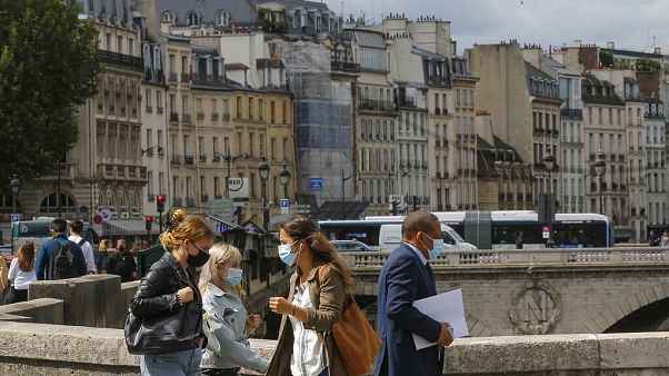 People cross the Petit-Pont-Cardinal-Lustiger bridge while wearing a protective face masks as a precaution against the coronavirus in Paris. People cross the Petit-Pont-Cardinal-Lustiger bridge while wearing a protective face masks as a precaution against the coronavirus in Paris.