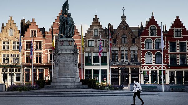 A woman wears a mouth mask as she walks in the Market Square in Bruges, Belgium. A woman wears a mouth mask as she walks in the Market Square in Bruges, Belgium.