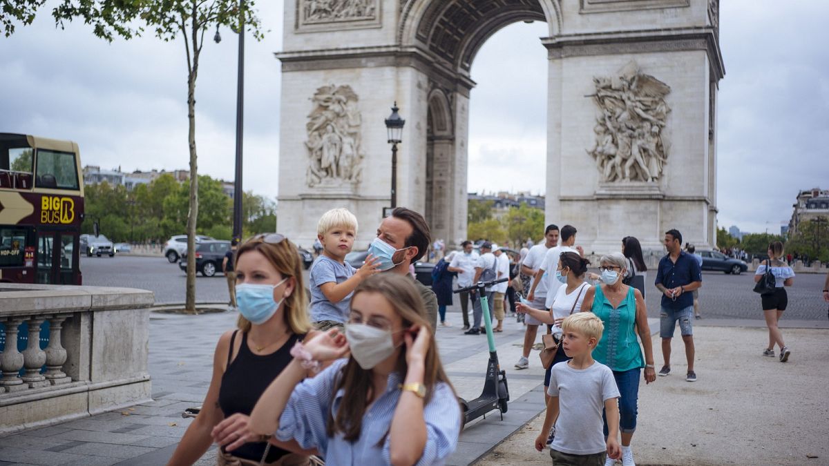 a family wearing protective face masks walk along on the Champs Elysee in Paris.
