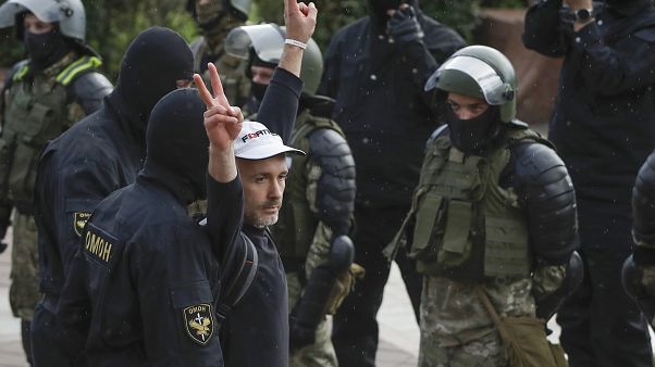 A man makes v-signs in front of a riot police blockade as he is detained during a protest at the Independence Square in Minsk, Belarus, Thursday, Aug. 27, 2020. A man makes v-signs in front of a riot police blockade as he is detained during a protest at the Independence Square in Minsk, Belarus, Thursday, Aug. 27, 2020.