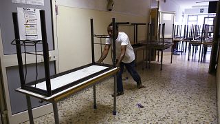 A worker pushes away the old double desks to be substituted by the new single ones for the start of the new school year, at the Isacco Newton high school institute in Rome Wed