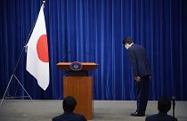 Şinzo Abe, konferans öncesinde Japon bayrağı önünde eğiliyor
