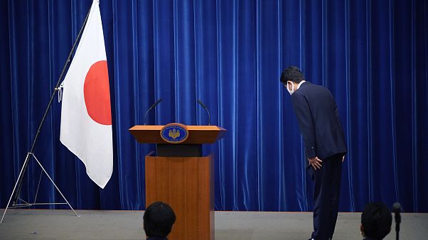 Şinzo Abe, konferans öncesinde Japon bayrağı önünde eğiliyor Şinzo Abe, konferans öncesinde Japon bayrağı önünde eğiliyor