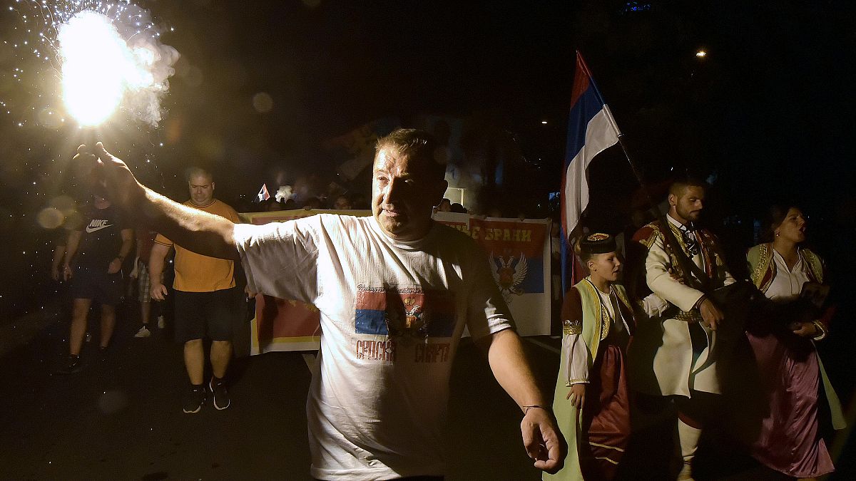 An opposition supporter lights torch during church-led protest in Podgorica, Montenegro, Thursday, Aug. 27, 2020. 