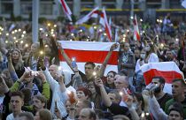 Belarusian opposition supporters with old Belarusian national flags light their smartphones as they gather at Independence Square in Minsk, Belarus, Tuesday, Aug. 25, 2020