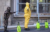 Participants of an exercise wear protective suits as they disinfect themselves in front of the Kutvolgyi hospital in Budapest.