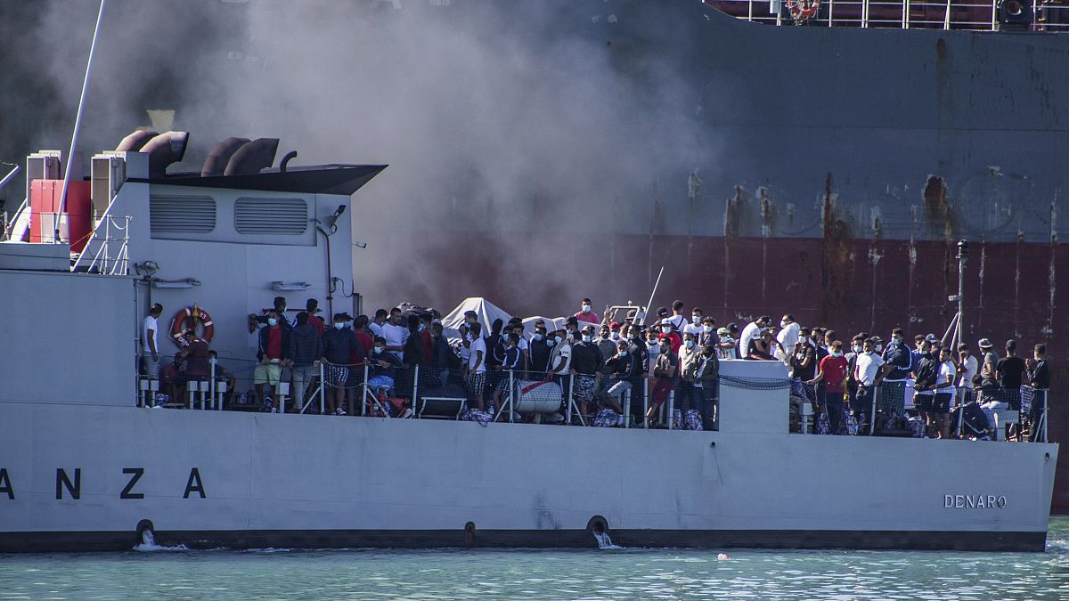 In this file photo taken on July 27, 2020, migrants arrive in Porto Empedocle, Sicily, aboard two military ships after being transferred from the island of Lampedusa
