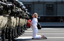 A woman kneels in front of a riot police line as they block Belarusian opposition supporters rally in the center of Minsk, Belarus, Sunday, Aug. 30, 2020