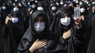 People wearing protective face masks to help prevent spread of the coronavirus mourn during an annual ceremony commemorating Ashoura.