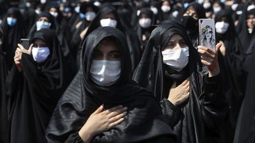People wearing protective face masks to help prevent spread of the coronavirus mourn during an annual ceremony commemorating Ashoura. 