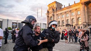Agentes de policía alejan a una multitud de manifestantes de la plaza 'Platz der Republik' frente al edificio del Reichstag durante una manifestación, el sábado 29 de agosto.