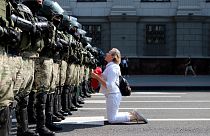 Una donna si inginocchia davanti agli agenti della polizia antisommossa, che blocca la manifestazione dei sostenitori dell'opposizione bielorussa, Minsk