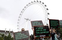 Extinction Rebellion climate change protesters and activists hold up placards in front of the London Eye. Friday, Aug. 28, 2020.
