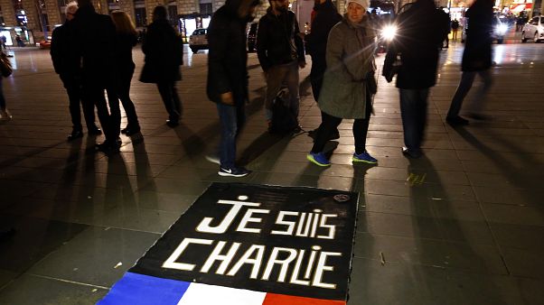 People walk around to banner reading "Je suis Charlie", "I am Charlie" on the Place de la Republique in Paris. January 7, 2016. People walk around to banner reading "Je suis Charlie", "I am Charlie" on the Place de la Republique in Paris. January 7, 2016.