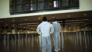 Utasok védőöltözékben a brüsszeli Zaventem repülőtéren