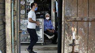 Wearing protective face masks to help prevent the spread of the coronavirus, a shopkeeper sits at his stall at the old grand bazaar of the city of Zanjan