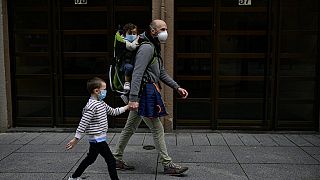 Un padre pasea con sus dos hijos por las calles de Madrid con una mascarilla quirúrgica