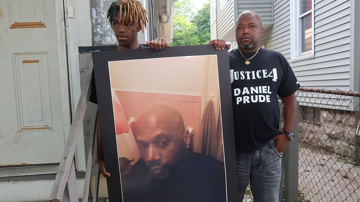 Joe Prude, brother of Daniel Prude, right, and his son Armin, stand with a picture of Daniel Prude in Rochester, New York