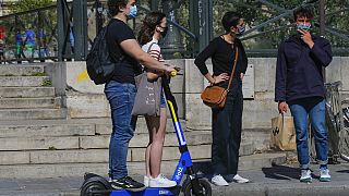 People wearing a protective face masks as precaution against the conoravirus ride a scooter in Paris